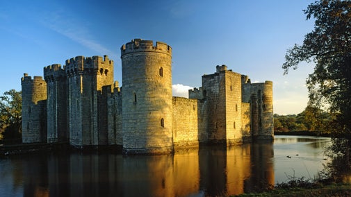 Sandstone medieval castle surrounded by a moat in the evening light
